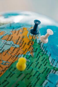 Detailed view of a globe with blue, white, and yellow pushpins marking locations.